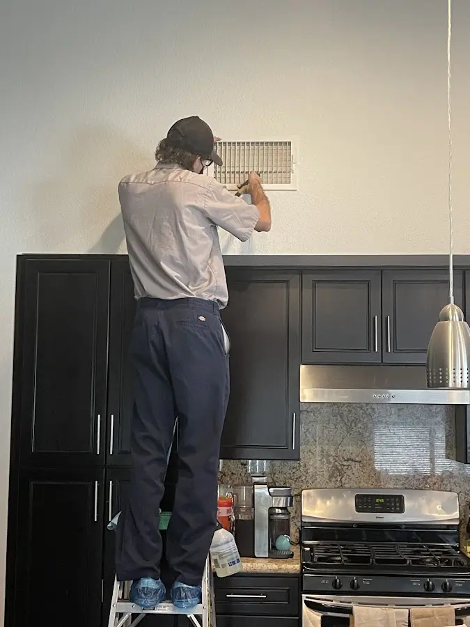 Technician inspecting an air vent during HVAC service in Valle Vista